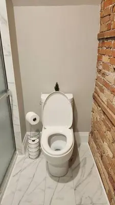 a white toilet in a bathroom with a brick wall at ENTIRE 1 BEDROOM APARTMENT ACROSS FROM GOOGLE - br5 in Kitchener