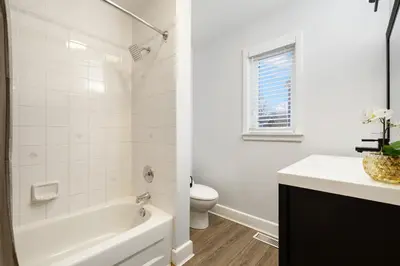 a white bathroom with a tub and a toilet at Luxurious Private House Pool and Hot Tub in Blue Mountains