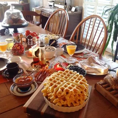 a wooden table with a waffle and food on it at Our Valley View Bed & Breakfast in Hampton