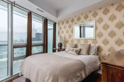 a bedroom with a large bed with a window at Two BD CN Tower and Lake Ontario View in Toronto