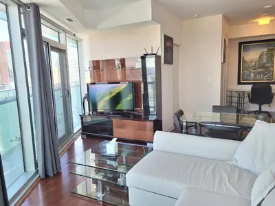a living room with a white couch and a tv at Two BD CN Tower and Lake Ontario View in Toronto