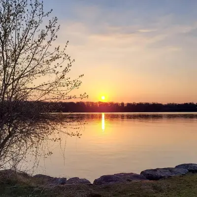 a sunset over a body of water with rocks at La Maison de Sophie in Niagara on the Lake