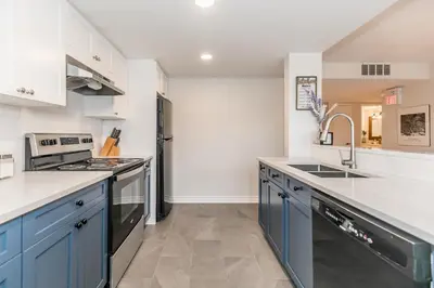 a kitchen with blue cabinets and a black refrigerator at Stunning Townhouse - 3 BDRM Blue Mountain Village Sauna! in Blue Mountains