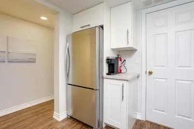 a stainless steel refrigerator in a kitchen with white cabinets at Wintergreen Retreat with Private Sauna & Patio 82291 in Blue Mountains