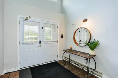a hallway with a white door and a table and a mirror at Wintergreen Retreat with Private Sauna & Patio 82291 in Blue Mountains