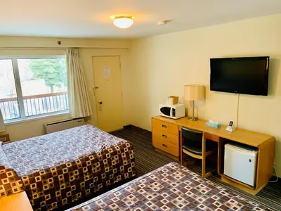 a hotel room with two beds and a desk with a tv at Toronto Lakeshore Hotel in Mississauga