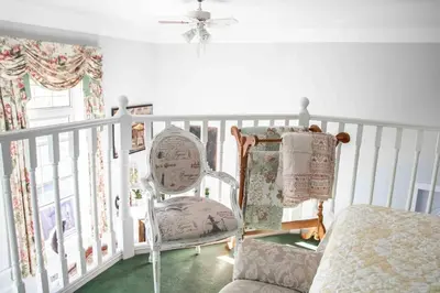 a white room with a chair and a ceiling fan at The Jypsy Inn Chambre Damour Bracebridge in Bracebridge