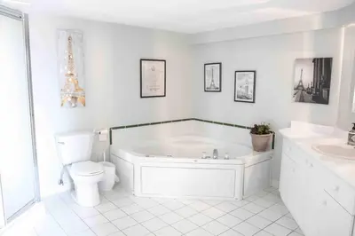 a white bathroom with a tub and a toilet at The Jypsy Inn Chambre Damour Bracebridge in Bracebridge