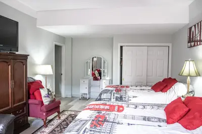 a bedroom with a bed and a red chair at The Jypsy Inn Notting Hill in Bracebridge