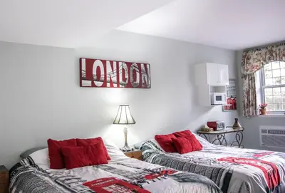 two beds in a room with red pillows at The Jypsy Inn Notting Hill in Bracebridge