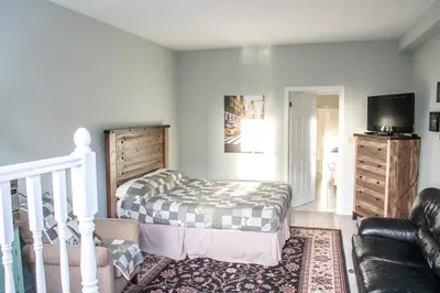 a bedroom with a bed and a couch and a tv at The Jypsy Inn / Fifth Avenue in Bracebridge