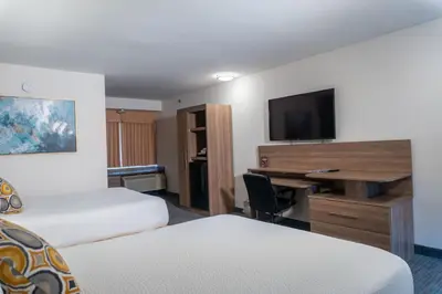 a hotel room with two beds and a desk with a television at Days Inn by Wyndham Niagara Falls Centre St By the Falls in Niagara Falls