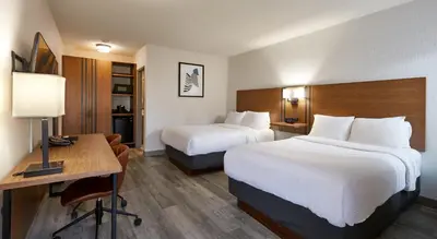 a hotel room with two beds and a desk at Canadas Best Value Inn Toronto in Toronto
