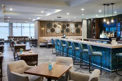 a restaurant with a bar and tables and chairs at Delta Hotels by Marriott Toronto Mississauga in Mississauga