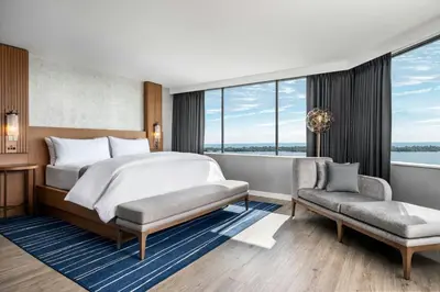 a bedroom with a bed and a chair and windows at The Westin Harbour Castle, Toronto in Toronto