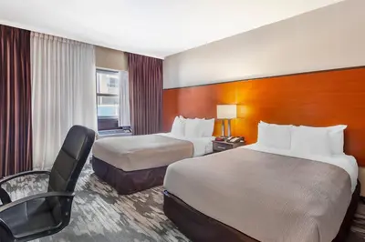 a hotel room with two beds and a chair at Quality Inn Toronto Airport in Mississauga