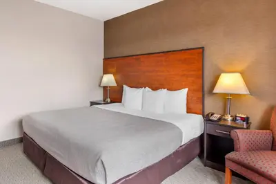 a hotel room with a large bed and a chair at Quality Inn Toronto Airport in Mississauga