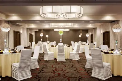 a banquet room with white tables and chairs and a chandelier at DoubleTree by Hilton Hotel Toronto Airport West in Mississauga