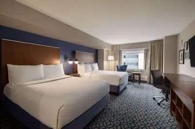 a hotel room with two beds and a desk at Wyndham Grand Fallsview Hotel in Niagara Falls