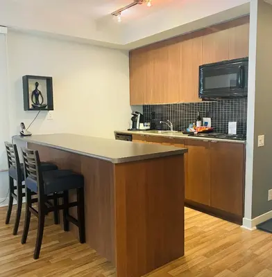 a kitchen with a counter and a bar with chairs at Executive Hotel Cosmopolitan Toronto in Toronto
