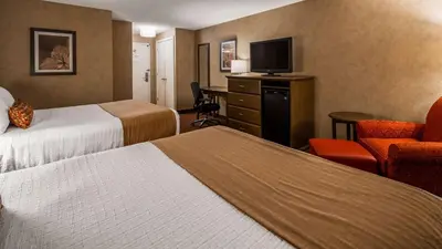 a hotel room with two beds and a desk and chair at Best Western Plus Cairn Croft Hotel in Niagara Falls