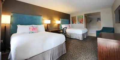 a hotel room with two beds and a desk at Old Stone Inn Boutique Hotel in Niagara Falls