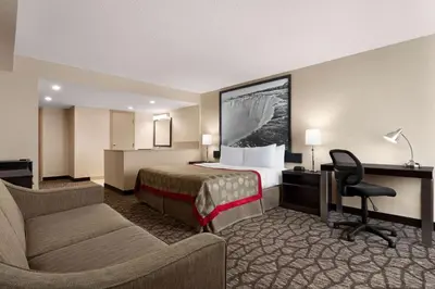 a hotel room with a bed and a desk at Ramada By Wyndham Niagara Falls near the Falls in Niagara Falls