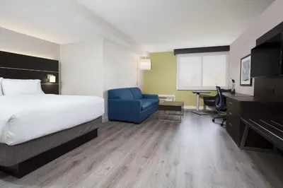 a hotel room with a bed and a blue chair at Holiday Inn Express & Suites Mississauga-Toronto Southwest by IHG in Mississauga