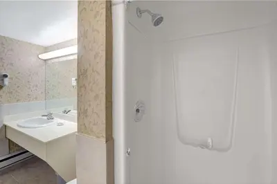 a bathroom with a shower with a sink and a mirror at Super 8 by Wyndham Niagara Falls North in Niagara Falls