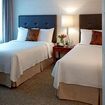 a hotel room with two beds and a table at Cambridge Suites Toronto in Toronto