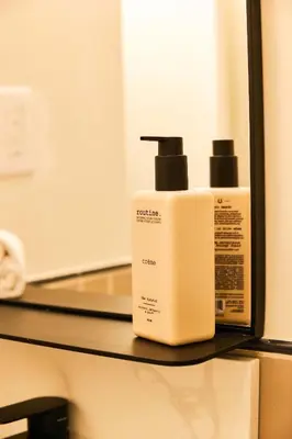 a white bottle of soap on a shelf next to a mirror at Union Hotel in Toronto