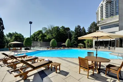 a swimming pool with tables and umbrellas next to a building at Crowne Plaza Toronto - North York by IHG in Toronto