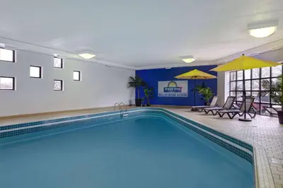 a pool in a hotel room with chairs and umbrellas at Days Inn by Wyndham Niagara Falls Near The Falls in Niagara Falls