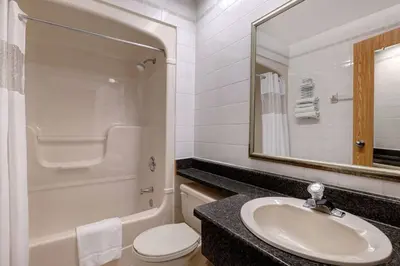 a bathroom with a sink and a toilet and a mirror at Days Inn by Wyndham Niagara Falls Near The Falls in Niagara Falls