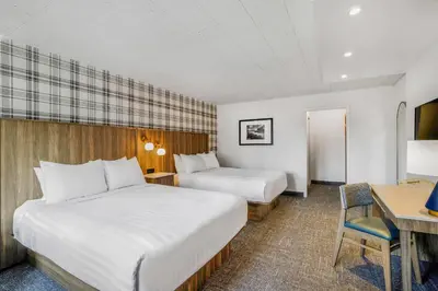 a hotel room with two beds and a desk at Travelodge by Wyndham Niagara Falls At the Falls in Niagara Falls
