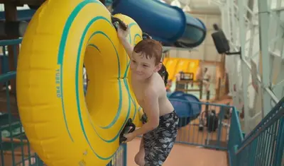 a young boy is standing next to a yellow tube at Americana Waterpark Resort & Spa in Niagara Falls