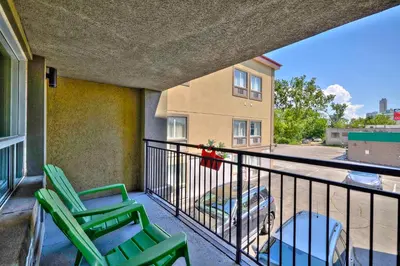 two green chairs on a balcony with a building at The Glengate Hotel & Suites in Niagara Falls