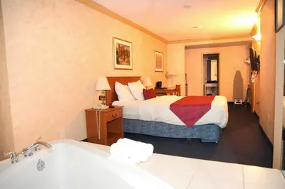 a hotel room with a bed and a bath tub at The Glengate Hotel & Suites in Niagara Falls