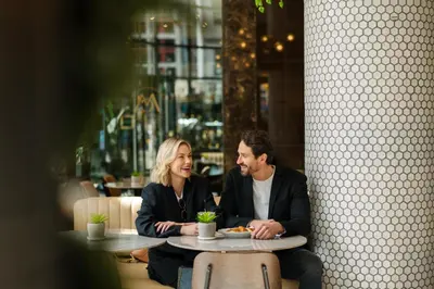 a man and woman sitting at a table in a restaurant at SoHo Hotel Toronto in Toronto