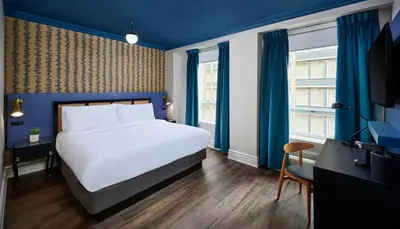 a hotel room with a bed and a tv at Hotel Victoria in Toronto