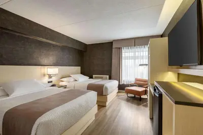 a hotel room with two beds and a television at Days Inn by Wyndham Toronto West Mississauga in Mississauga