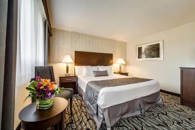 a hotel room with a bed and flowers on a table at Monte Carlo Inn Oakville Suites in Oakville