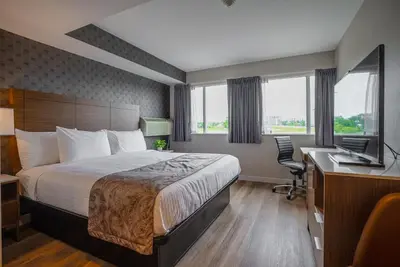 a hotel room with a bed and a desk with a computer at Monte Carlo Inn Oakville Suites in Oakville