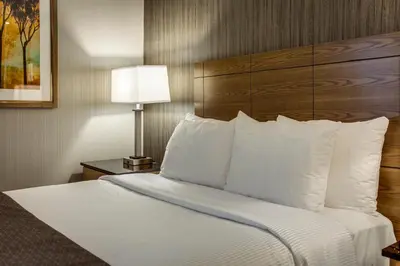 a hotel room with a bed with white pillows at Monte Carlo Inn Airport Suites in Mississauga
