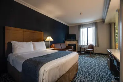 a hotel room with a large bed and a chair at Monte Carlo Inn Toronto West Suites in Mississauga