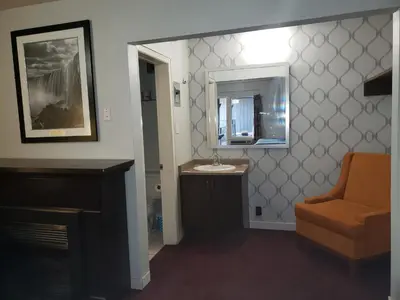 a bathroom with a sink and a mirror and a chair at Niagara Falls Courtside Inn in Niagara Falls