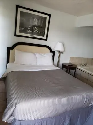 a bedroom with a large bed and a bath tub at Niagara Falls Courtside Inn in Niagara Falls