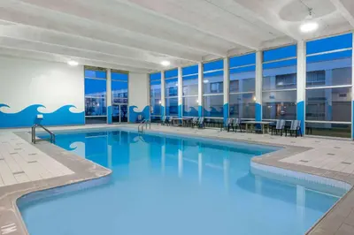 a large swimming pool with tables and chairs in a building at Ramada by Wyndham London in London
