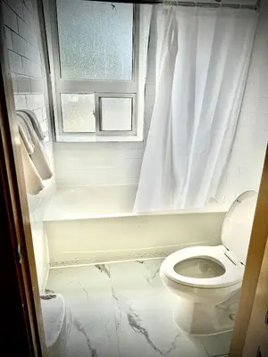 a white bathroom with a toilet and a window at Royal Oak Inn in Toronto