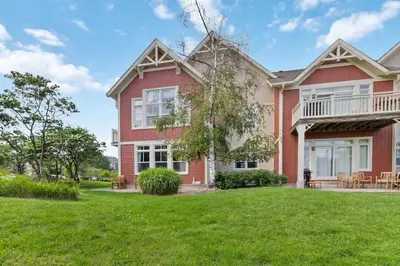 a large red house with a yard at Rivergrass Townhouse in Blue with Pool Golf Skiing - 219 Rivergrass in Blue Mountains